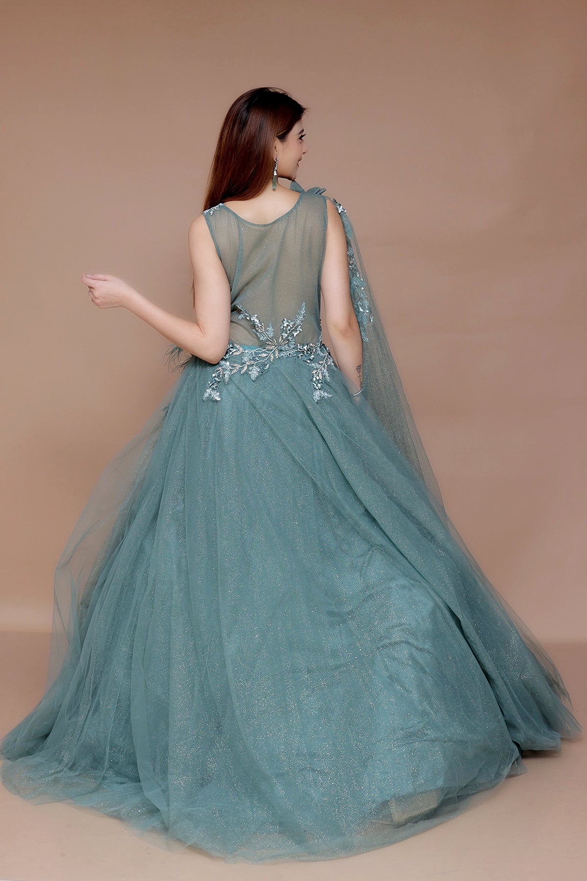 Bottle Green Gown in Net embellished with hand embroidery on yolk along with cape sleeve
